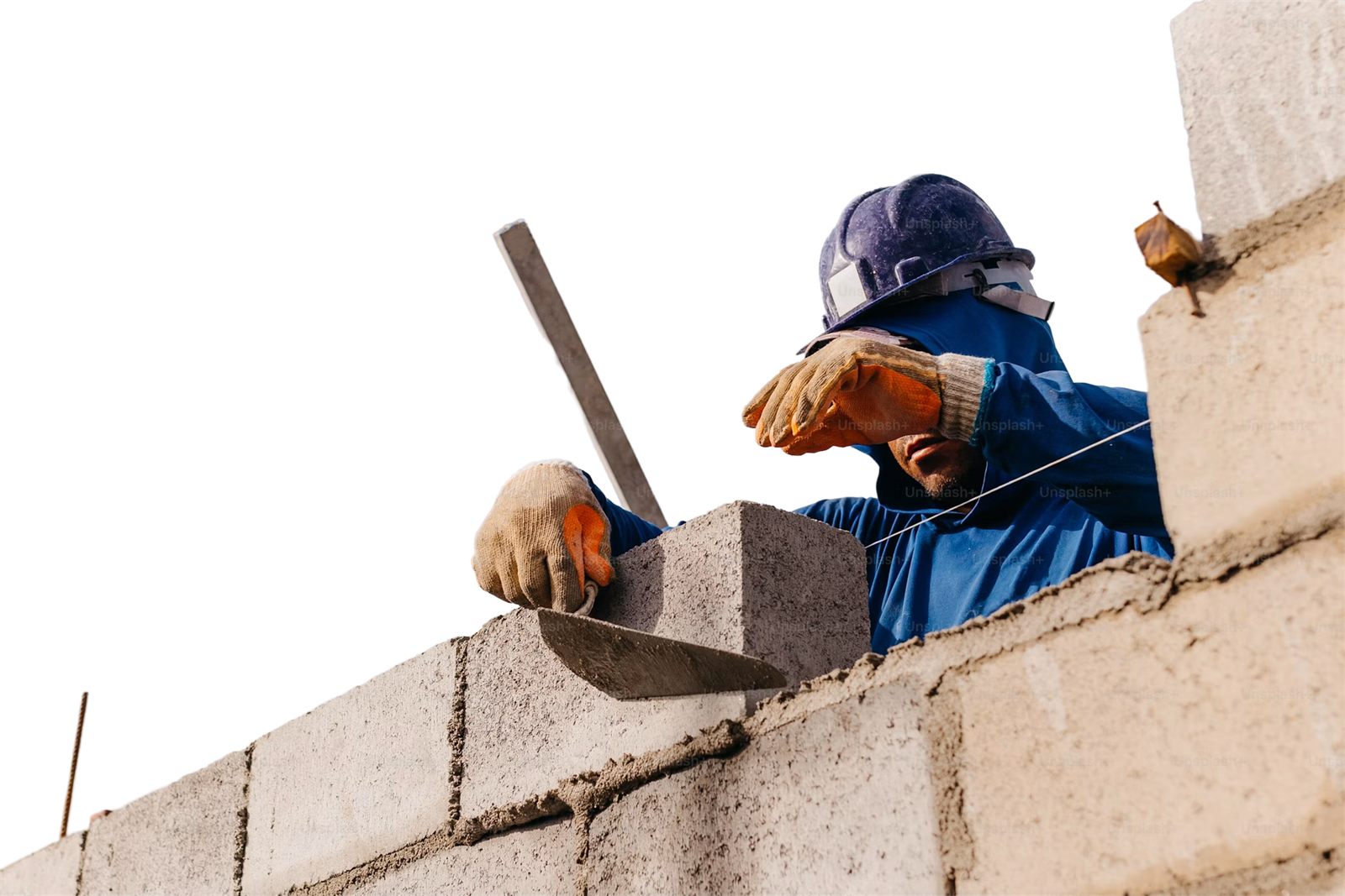 A mason laying a concrete block on a wall under construction